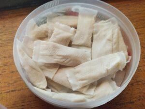 Nicotine pouches in a round container on a wooden surface.